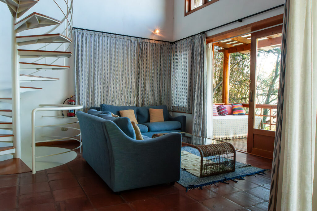 Villa Bambu living room with blue sofa, spiral staircase, and balcony view.