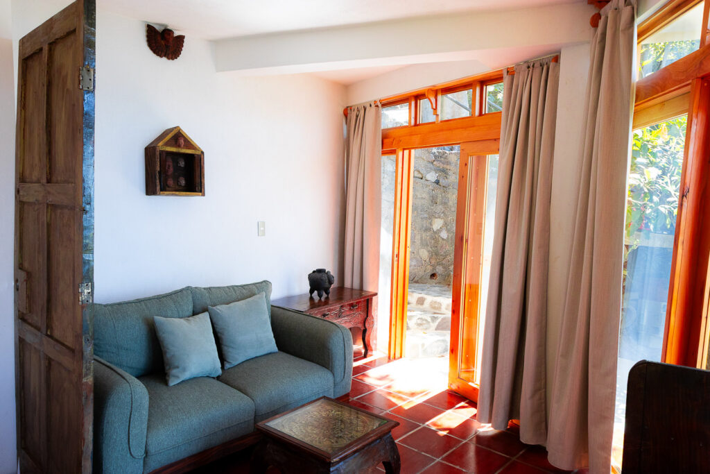 Villa Gio living room with sofa, terracotta tile floor, and open doors to the outside.
