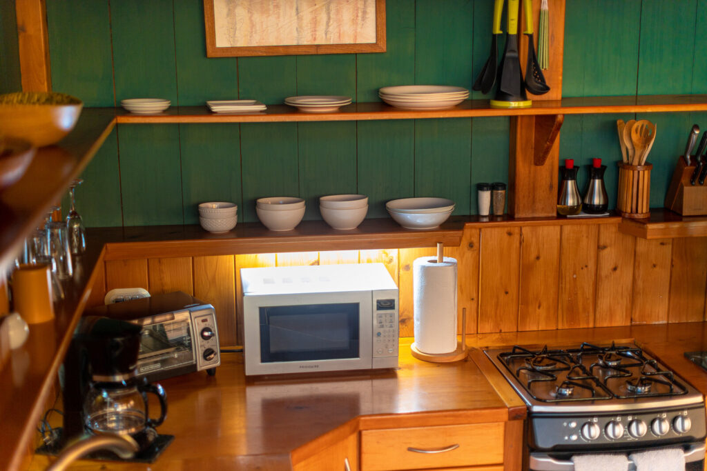 Villa Jade kitchen with green walls, wooden shelves, microwave, toaster, and stove.