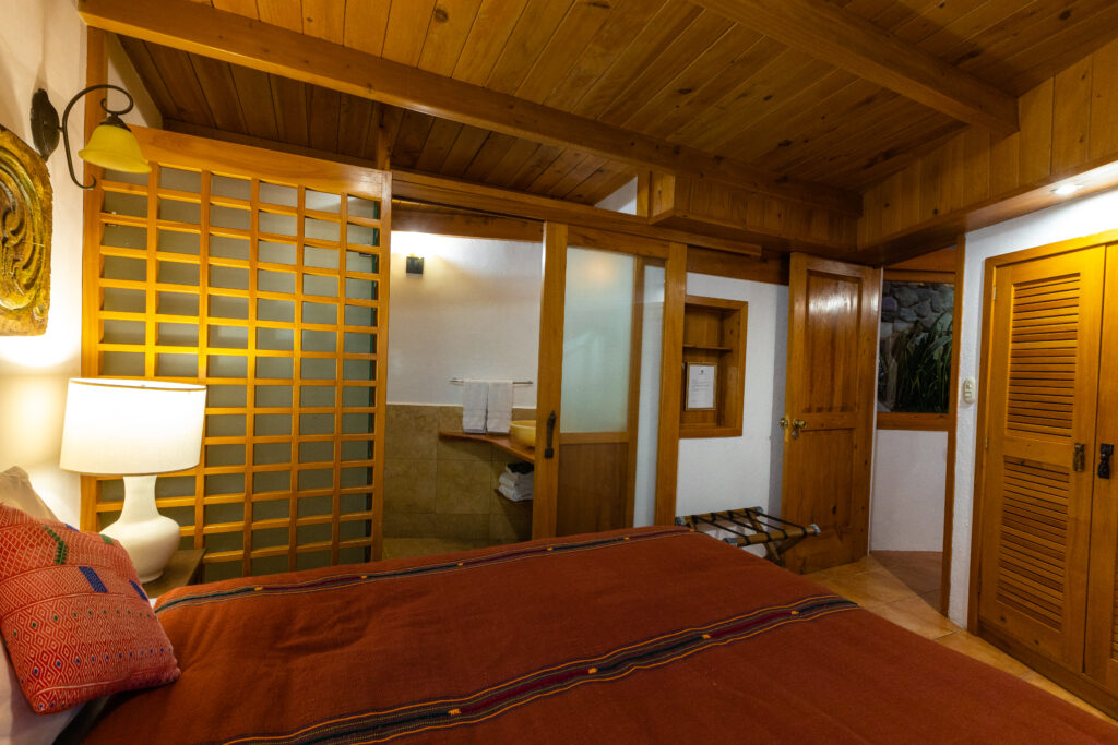 Interior of a Villa Loft bedroom with wooden accents and a sliding door to the bathroom.