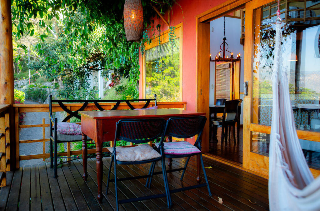 Villa Mirador: Outdoor dining area with table, chairs, and lush greenery, inviting ambiance.